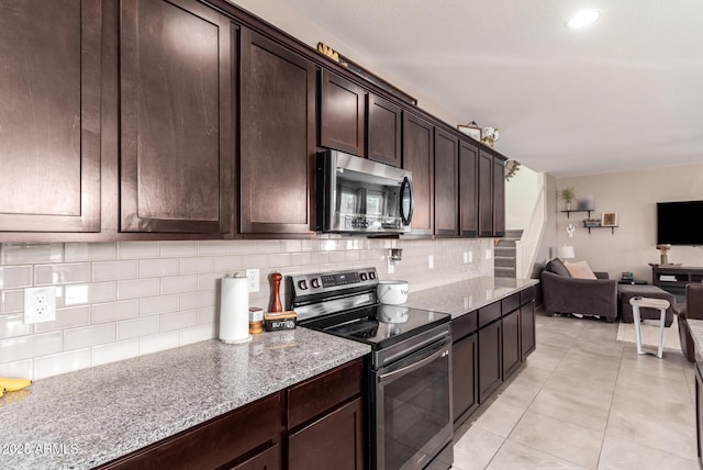 kitchen with light tile patterned floors, appliances with stainless steel finishes, backsplash, dark brown cabinets, and light stone counters