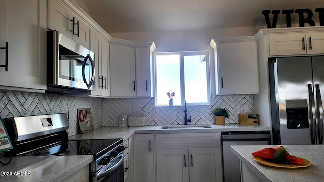 kitchen with sink, decorative backsplash, white cabinets, and appliances with stainless steel finishes