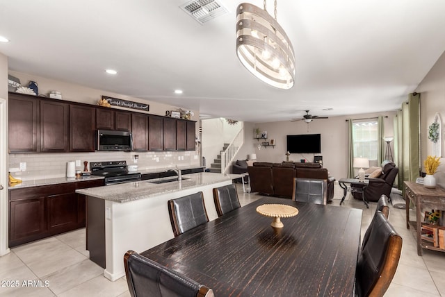 kitchen with dark brown cabinetry, sink, tasteful backsplash, a center island with sink, and range with electric stovetop