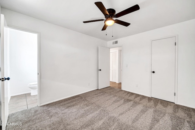 unfurnished bedroom with ensuite bath, ceiling fan, a closet, and light carpet