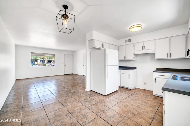 kitchen featuring pendant lighting, white refrigerator, light tile patterned flooring, and white cabinetry