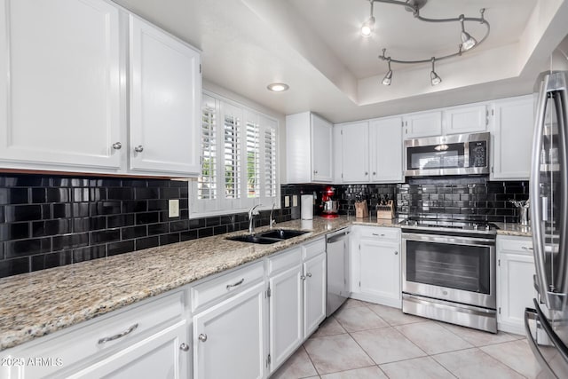 kitchen with white cabinets, a raised ceiling, appliances with stainless steel finishes, and tasteful backsplash