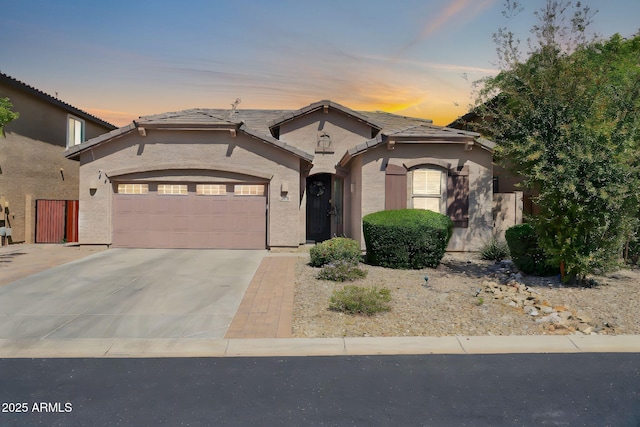 view of front of house featuring a tile roof, a garage, driveway, and stucco siding