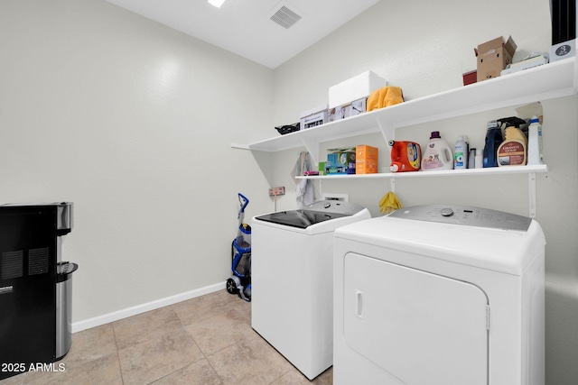washroom featuring baseboards, washing machine and dryer, visible vents, and laundry area