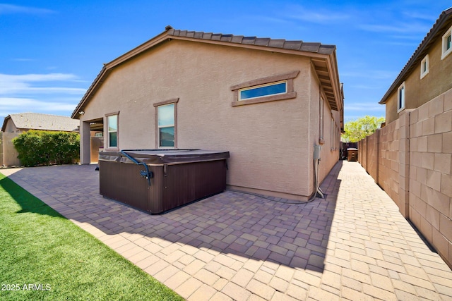 back of property featuring a fenced backyard, a hot tub, and a patio area