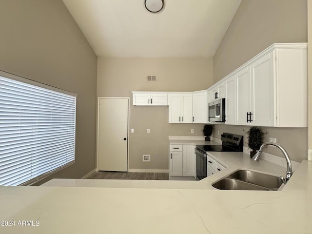 kitchen with sink, stainless steel appliances, hardwood / wood-style floors, vaulted ceiling, and white cabinets