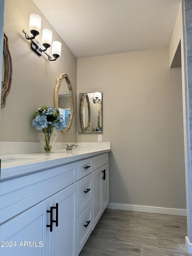 bathroom featuring wood-type flooring, vanity, and a textured ceiling