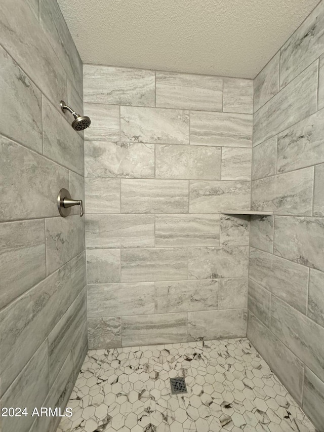 bathroom featuring a textured ceiling and tiled shower