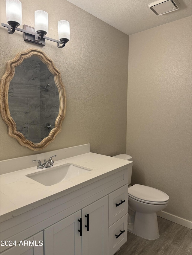 bathroom with toilet, vanity, a textured ceiling, and hardwood / wood-style flooring