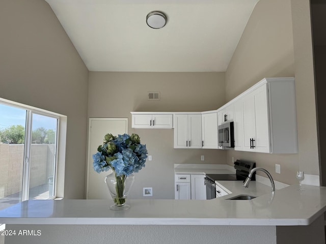 kitchen with high vaulted ceiling, sink, appliances with stainless steel finishes, white cabinetry, and kitchen peninsula