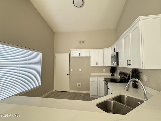 kitchen with white cabinets, sink, stainless steel appliances, and high vaulted ceiling