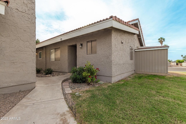 view of property exterior featuring a yard, a tile roof, and stucco siding