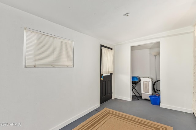 spare room featuring concrete floors and baseboards