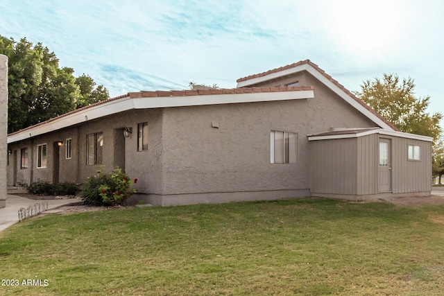 view of side of property featuring a lawn and stucco siding