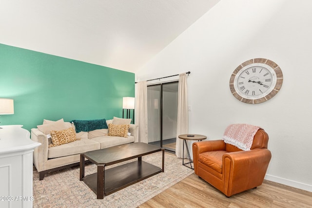 living room featuring light wood finished floors, baseboards, and vaulted ceiling