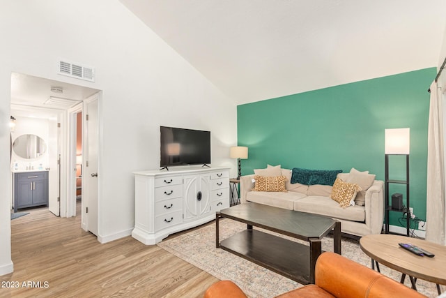 living area featuring high vaulted ceiling, baseboards, visible vents, and light wood finished floors