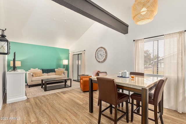 dining space featuring high vaulted ceiling, beam ceiling, and light wood-style flooring