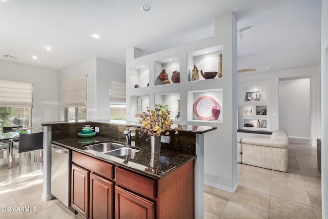 kitchen with dishwasher, sink, an island with sink, and dark stone counters