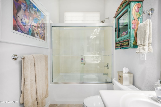 bathroom with combined bath / shower with glass door and toilet