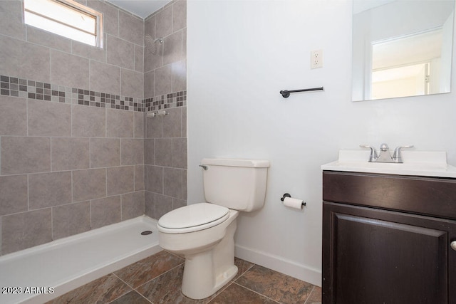 bathroom with tile floors, toilet, a tile shower, and vanity