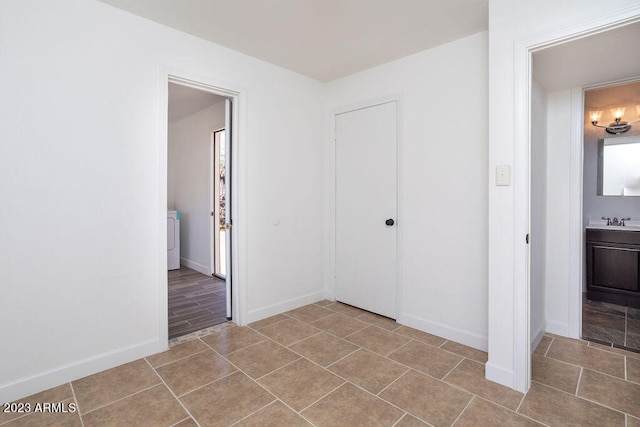 unfurnished bedroom featuring washer / dryer, hardwood / wood-style flooring, a closet, connected bathroom, and sink