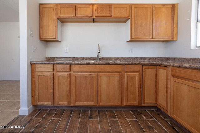 kitchen with dark stone counters, dark wood-type flooring, and sink