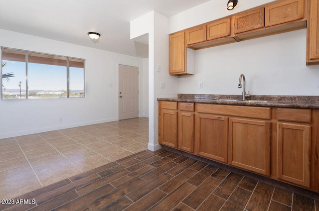 kitchen featuring sink, dark wood-type flooring, and dark stone countertops