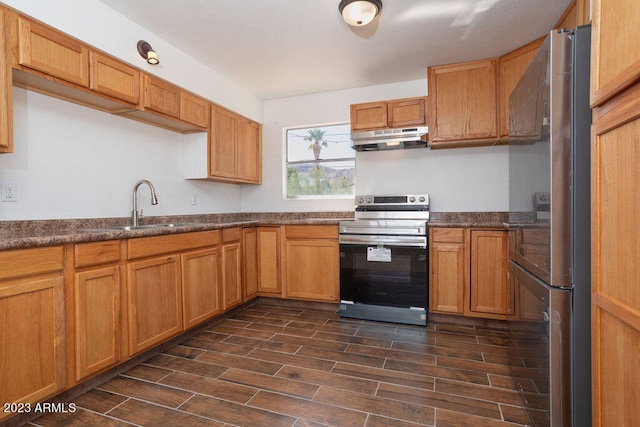 kitchen with sink, dark stone counters, stainless steel refrigerator, and electric range