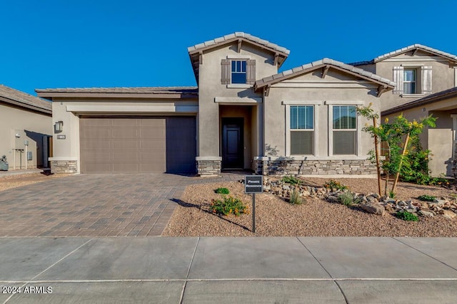 view of front of house with stone siding, stucco siding, decorative driveway, and a garage