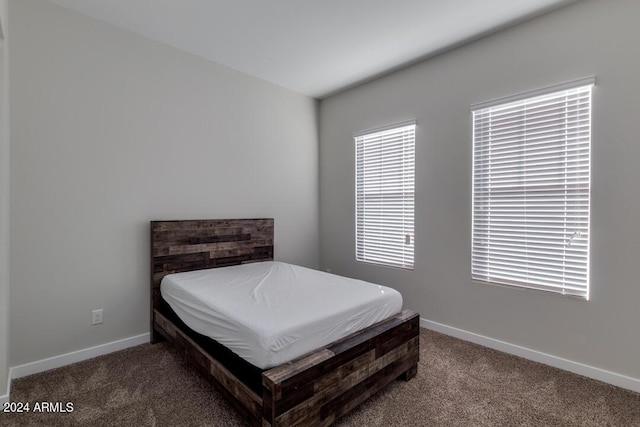 carpeted bedroom featuring multiple windows and baseboards