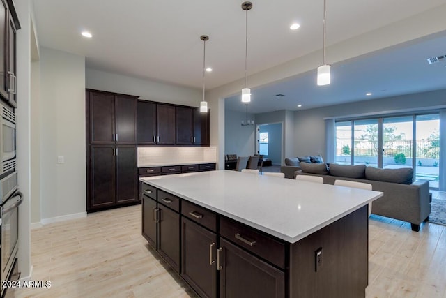 kitchen with light countertops, light wood-style flooring, dark brown cabinets, and backsplash