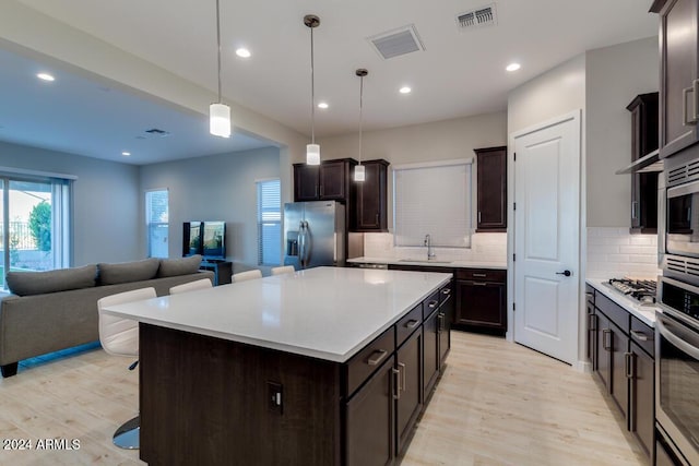 kitchen featuring visible vents, stainless steel appliances, open floor plan, and a sink