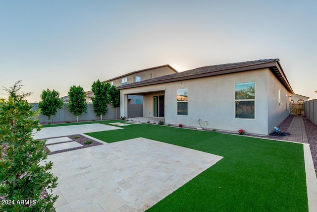 rear view of property featuring a yard, a patio area, a fenced backyard, and stucco siding