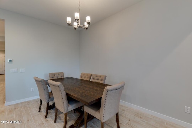 dining area featuring a notable chandelier, baseboards, and light wood finished floors