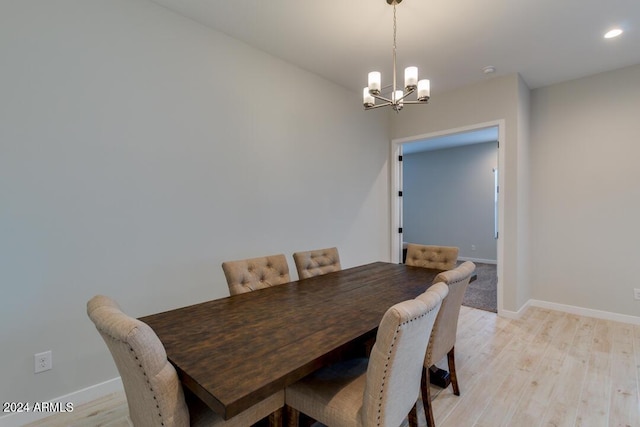 dining space with a notable chandelier, baseboards, and light wood-style floors