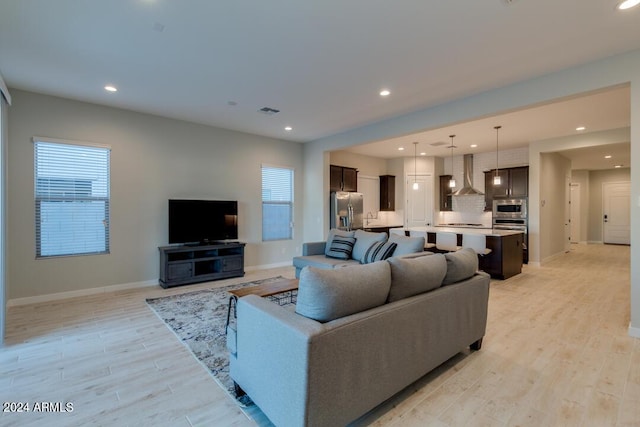 living room with recessed lighting, light wood-style flooring, visible vents, and baseboards