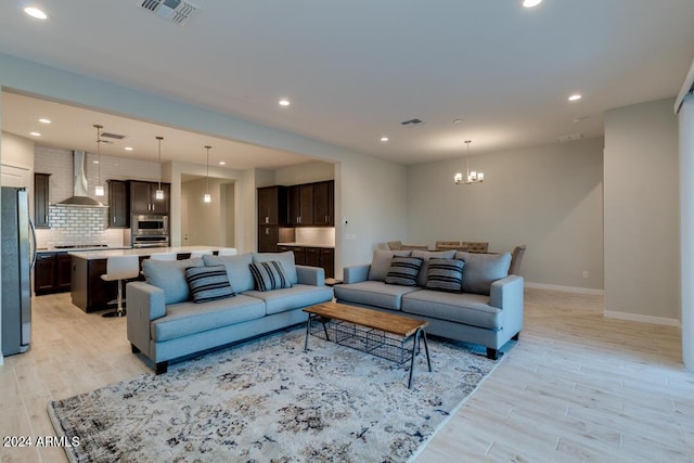 living room with recessed lighting, visible vents, light wood-style floors, and a notable chandelier