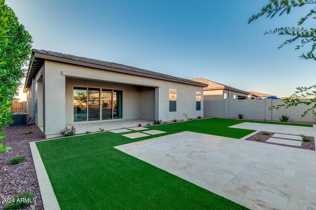 rear view of property with a patio area, stucco siding, a yard, and fence