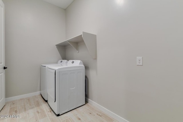 washroom with baseboards, light wood finished floors, laundry area, and washer and clothes dryer