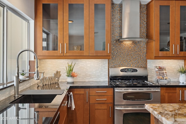 5802 E Spring Rd, Scottsdale, AZ 85254 - kitchen featuring range with two ovens, wall chimney range hood, a sink, brown cabinets, and tasteful backsplash