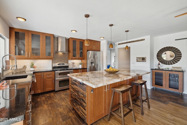 5802 E Spring Rd, Scottsdale, AZ 85254 - kitchen featuring appliances with stainless steel finishes, wall chimney range hood, a sink, brown cabinetry, and dark wood-style floors