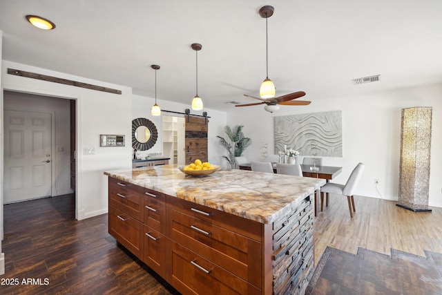 5802 E Spring Rd, Scottsdale, AZ 85254 - kitchen with a barn door, ceiling fan, dark wood-type flooring, hanging light fixtures, and a center island