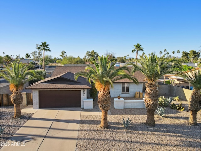 5802 E Spring Rd, Scottsdale, AZ 85254 - view of front of home featuring an attached garage, concrete driveway, brick siding, fence, and roof with shingles