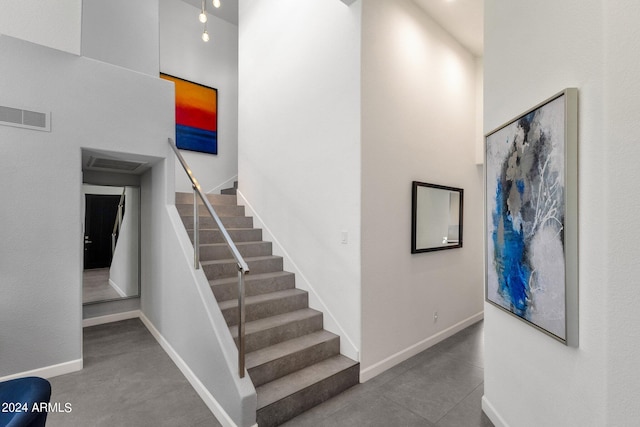 stairs featuring dark tile flooring and a towering ceiling