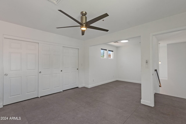 unfurnished bedroom featuring dark tile flooring, ceiling fan, and a closet