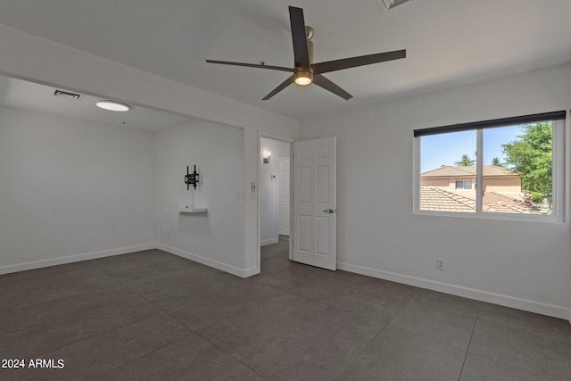 spare room featuring ceiling fan and dark tile floors