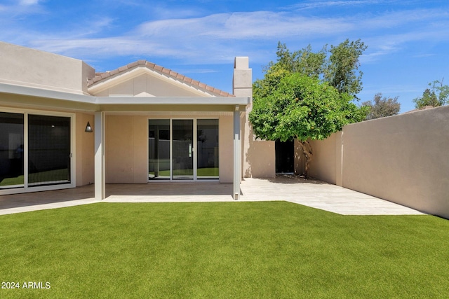 back of house with a yard and a patio