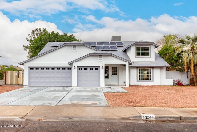 view of front of property featuring solar panels, stucco siding, fence, a garage, and driveway