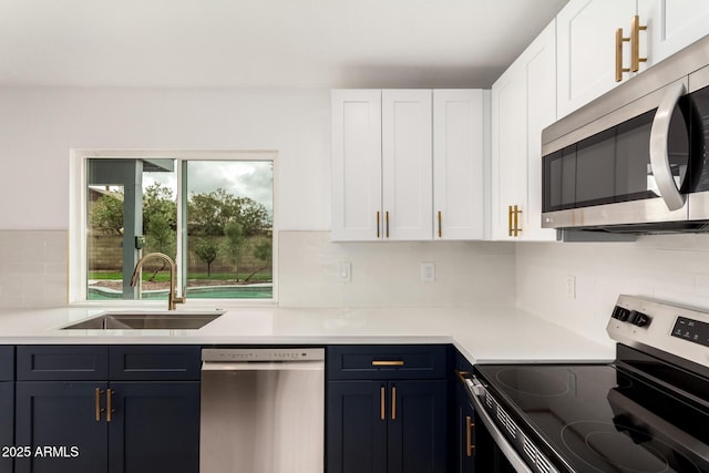 kitchen featuring stainless steel appliances, light countertops, a sink, and white cabinetry