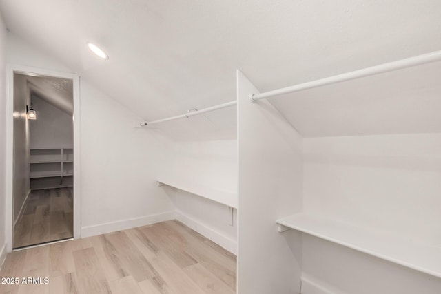 walk in closet with lofted ceiling and wood finished floors